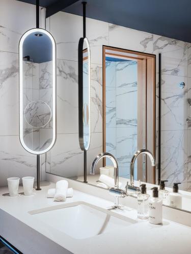 a bathroom with a sink and two mirrors at AMERON Zürich Bellerive au Lac in Zürich