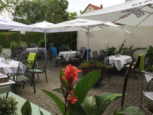 a patio with tables and chairs with white umbrellas at Hotel-Restaurant Wilhelmsbad in Seesen