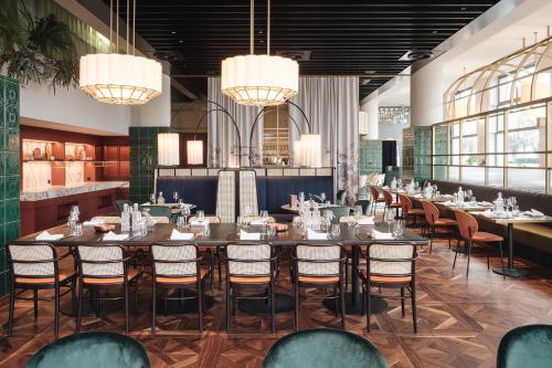 a dining room with tables and chairs and chandeliers at AMERON Zürich Bellerive au Lac in Zürich