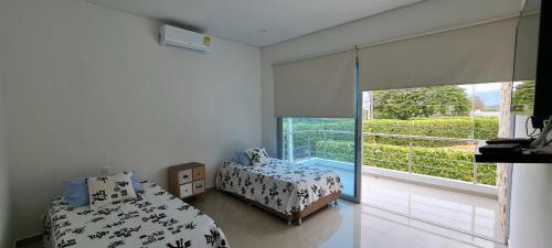 a bedroom with two beds and a large window at Casa Campestre en Condominio Lagos Del Peñon in Girardot