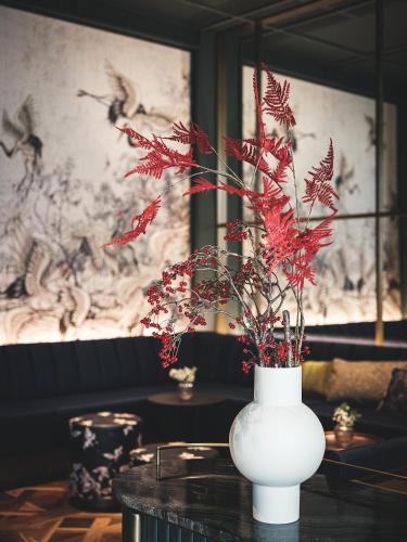 a white vase with red flowers on a table at AMERON Zürich Bellerive au Lac in Zürich