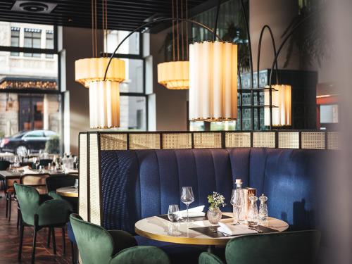 a dining room with tables and chairs and chandeliers at AMERON Zürich Bellerive au Lac in Zürich
