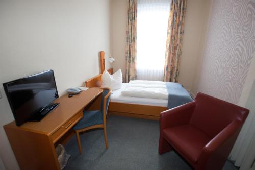 a hotel room with a desk and a bed and a television at Hotel-Restaurant Wilhelmsbad in Seesen