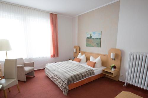 a hotel room with a bed and a chair at Hotel-Restaurant Wilhelmsbad in Seesen