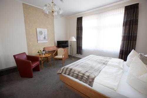 a bedroom with a bed and a desk and a chair at Hotel-Restaurant Wilhelmsbad in Seesen