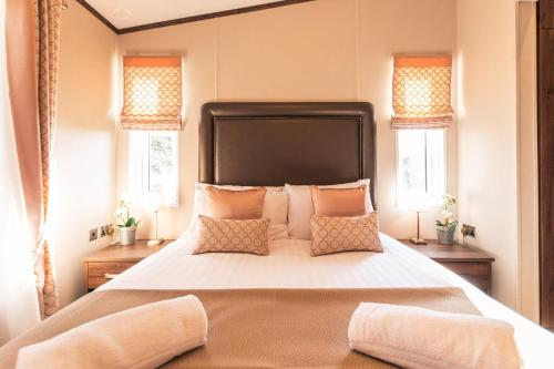 Un dormitorio con una cama grande y dos ventanas. en Sutton Lodge with Hot Tub, en York
