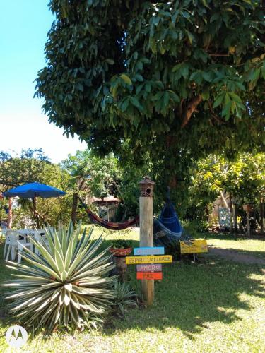 a sign in the grass next to a tree at Pousada Estrela do Mar in Barra Grande