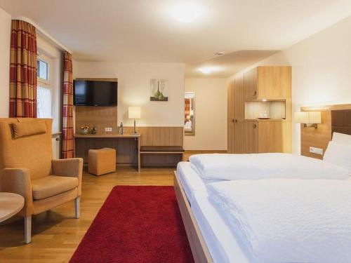 um grande quarto de hotel com uma cama e uma cadeira em Gasthof Belchenblick em Münstertal
