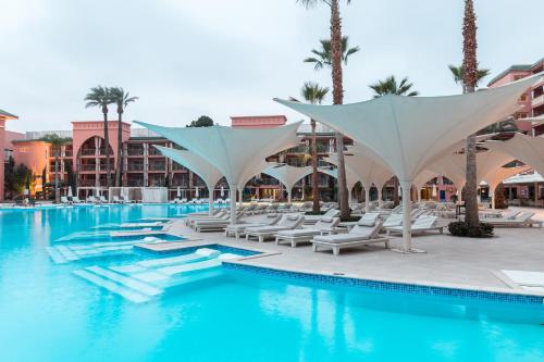 a pool at a resort with white umbrellas at Savoy Le Grand Hotel Marrakech in Marrakech