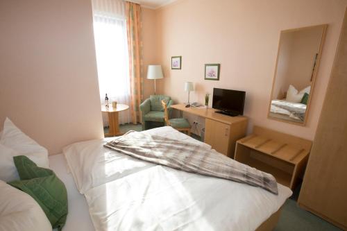 a bedroom with a bed and a desk with a television at Hotel-Restaurant Wilhelmsbad in Seesen