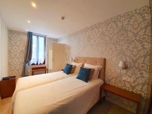 a bedroom with two beds and a wall with wallpaper at Croix Blanche de Sologne in Chaumont-sur-Tharonne