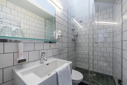 un bagno piastrellato bianco con lavandino e servizi igienici di Stift St. Georgen am Längsee a Sankt Georgen am Längsee