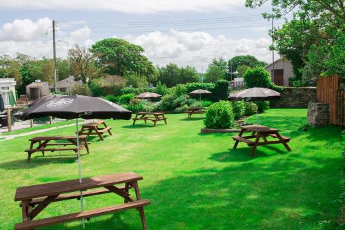 a group of picnic tables with an umbrella in the grass at The Valley Hotel, Anglesey in Valley