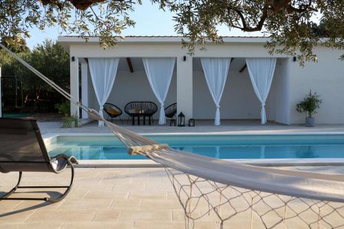 una hamaca frente a una casa con piscina en Stone Villa Olea, en Supetar