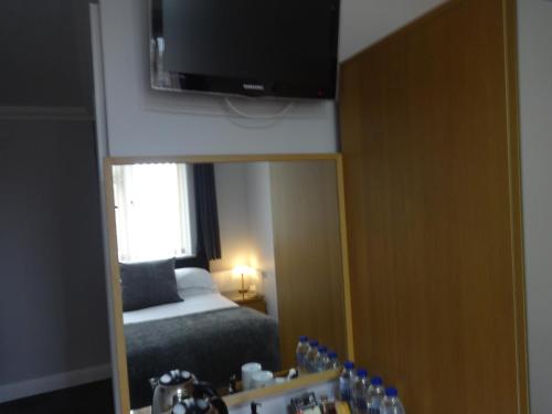 a bedroom with a bed and a mirror and a television at Autumn House in Cambridge