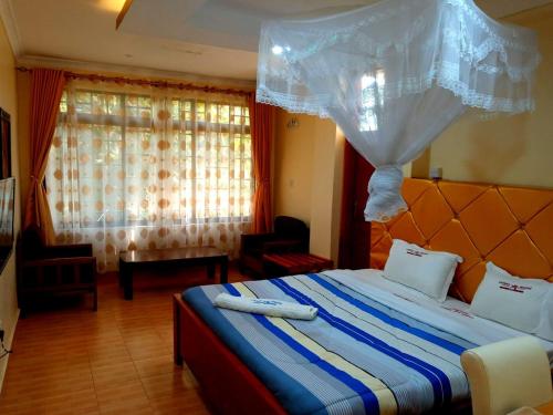 a bedroom with a bed with a blue and white comforter at Vienna Woods Hotel Nakuru in Nakuru