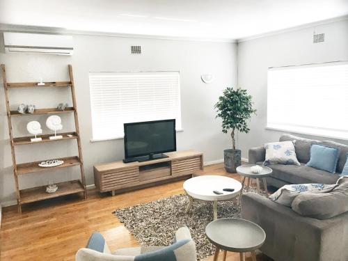 a living room with a couch and a flat screen tv at Melkbos Holiday Accommodation in Melkbosstrand