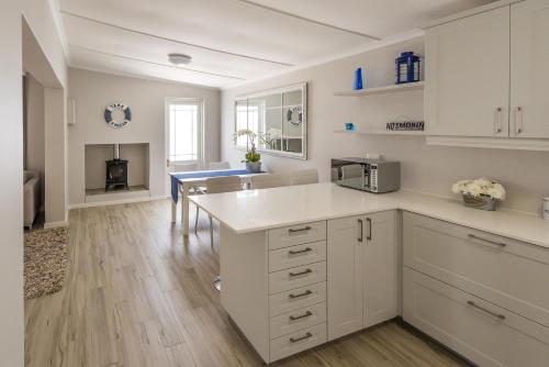 cocina con armarios blancos y encimera en Melkbos Holiday Accommodation en Melkbosstrand