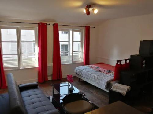 a bedroom with a bed and red curtains and a couch at STUDIO cosy dans le centre de LIMOGES in Limoges