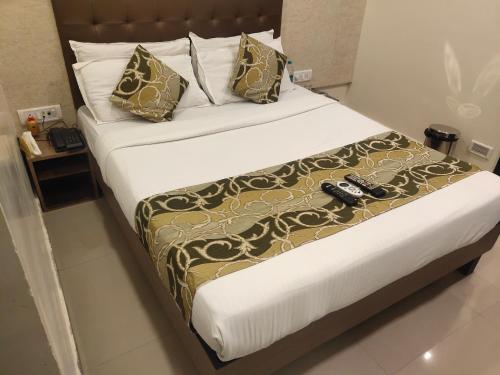 a bed in a hotel room with two remote controls on it at Hotel Golden Nest Popular Residency in Mumbai