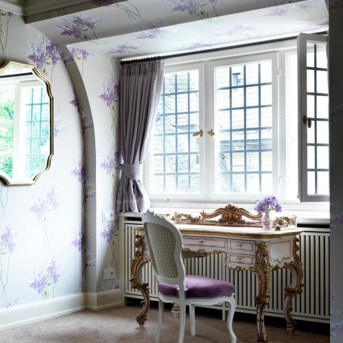 a room with a desk and a window with purple flowers at Schlosshotel Kronberg - Hotel Frankfurt in Kronberg im Taunus