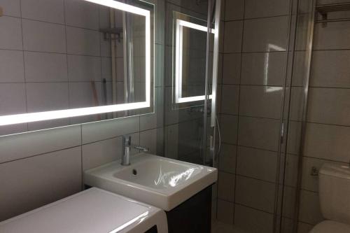 Un baño con lavabo, espejo e inodoro. en Studio lumineux avec balcon 2/4 pers. plein centre, en La Bourboule