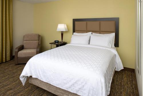 a bedroom with a large white bed and a chair at Candlewood Suites Olathe by IHG in Olathe
