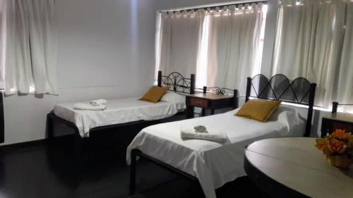 a room with three beds and a table and windows at Nuevas Cabañas Del Sol in San Lorenzo