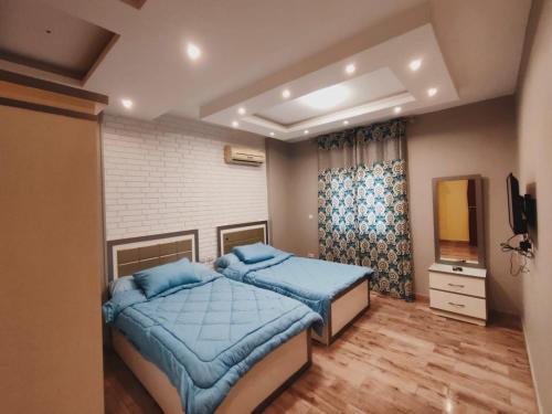 a bedroom with two beds and a television in it at Ramco For Furnished Apartments And Accommodation Compound Leila in Cairo