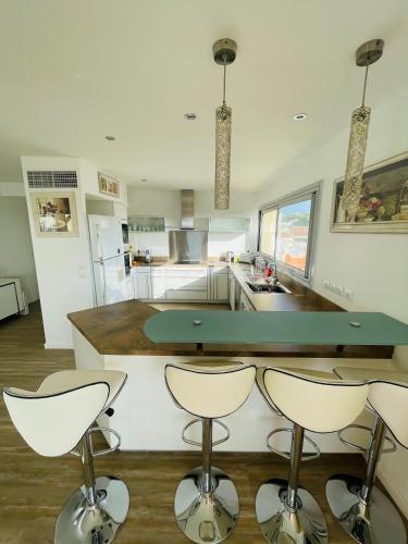 une cuisine avec un comptoir et quatre tabourets de bar dans l'établissement Grand appartement - Central Beach - Résidence de la Rose, à Sainte-Maxime