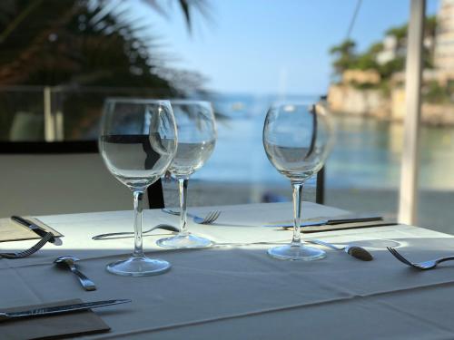 three wine glasses sitting on top of a table at Hotel Apartamentos Cala Santanyi in Cala Santanyi