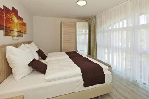 een slaapkamer met een groot bed met witte lakens en een raam bij Der Landhof Schwalbennest LH-204 in Stolpe auf Usedom