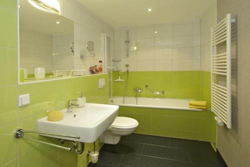 a green bathroom with a toilet and a sink at Der Landhof Schwalbennest LH-204 in Stolpe auf Usedom