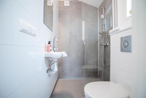 een badkamer met een douche, een toilet en een wastafel bij BUDDHA BEACH BUNGALOWS Adults Only in Zandvoort