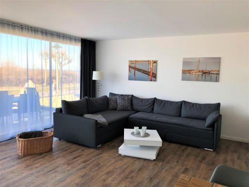 a living room with a black couch and a table at Meeresrauschen in Laboe