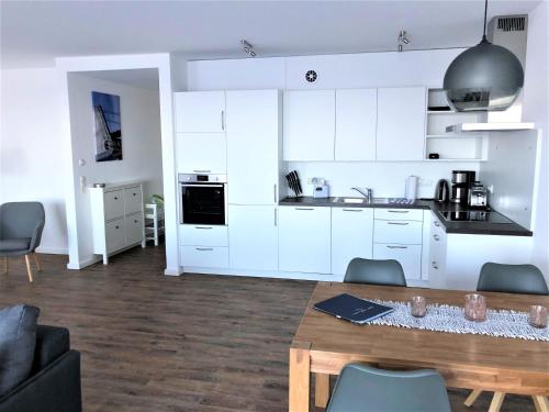 a kitchen with white cabinets and a wooden table at Meeresrauschen in Laboe