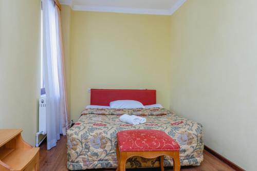 a bedroom with a bed with a red headboard and a stool at Hotel Lileo in Mestia