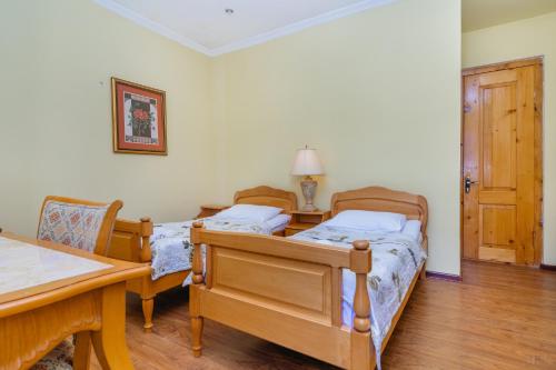 two beds in a room with a table and chairs at Hotel Lileo in Mestia