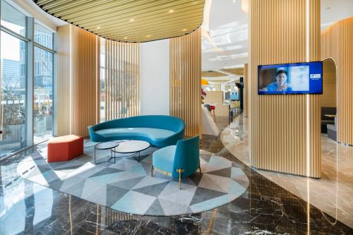 a lobby with chairs and a tv on a wall at Holiday Inn Express Shanghai Pudong Zhangjiang by IHG - 20 minutes to New International Expo Center and Disneyland in Shanghai