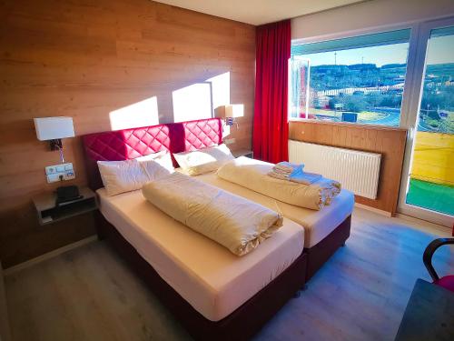 a bedroom with two beds and a large window at Meister BÄR HOTEL Frankenwald in Berg