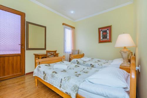 a bedroom with two beds and a lamp and a window at Hotel Lileo in Mestia