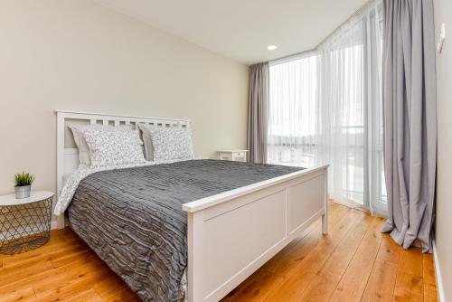 a bedroom with a large bed and a large window at Irklo apartamentai su vaizdu į jūrą in Šventoji