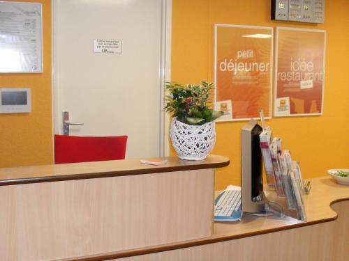 a reception desk with a vase of flowers on the counter at Premiere Classe Liege / Luik in Liège