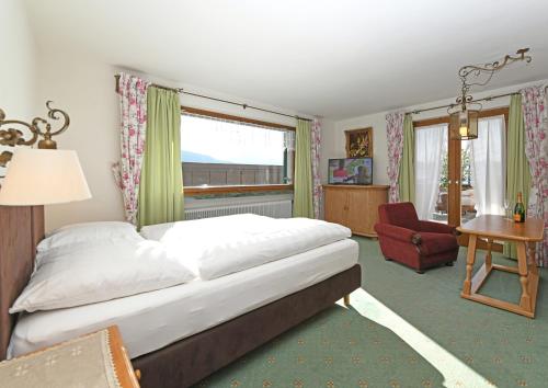 a bedroom with a bed and a desk and a chair at Hotel St Hubertus in Egg