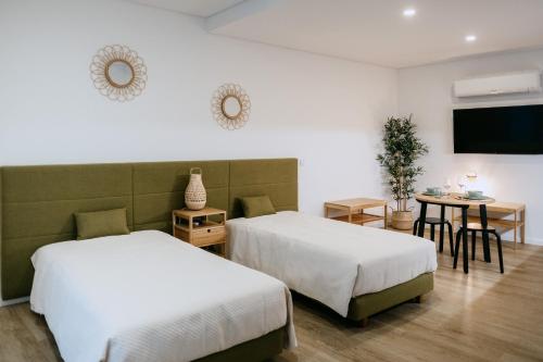 two beds in a room with a table and a tv at Villa Teresa apartamentos in Vila Nova de Gaia