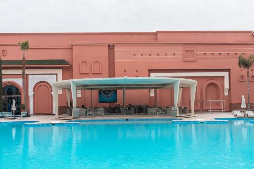 a large swimming pool in front of a pink building at Savoy Le Grand Hotel Marrakech in Marrakech