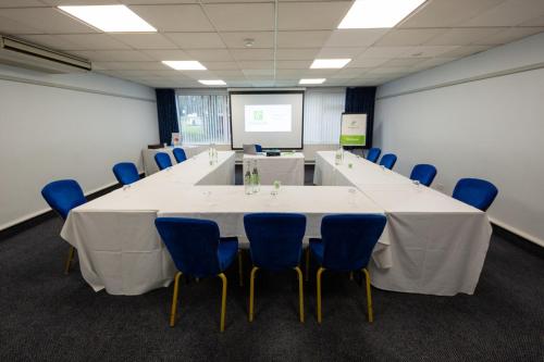 a conference room with a long table and blue chairs at Holiday Inn Newport by IHG in Newport