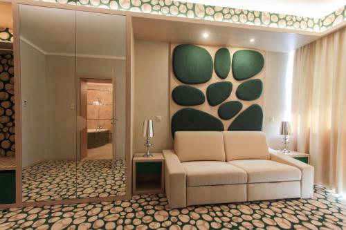 a living room with a couch and a painting on the wall at Hotel Aurum Family "A" in Hajdúszoboszló