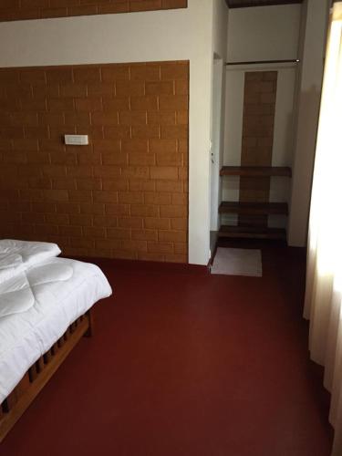 a bedroom with a bed and a brick wall at Coorg -Kunji Phad River View Homestay in Virajpet