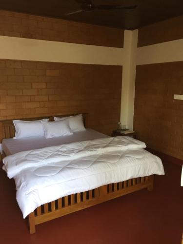 a large bed with white sheets and pillows at Coorg -Kunji Phad River View Homestay in Virajpet